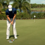 Golfer at address position preparing to strike a putt during focused practice session.