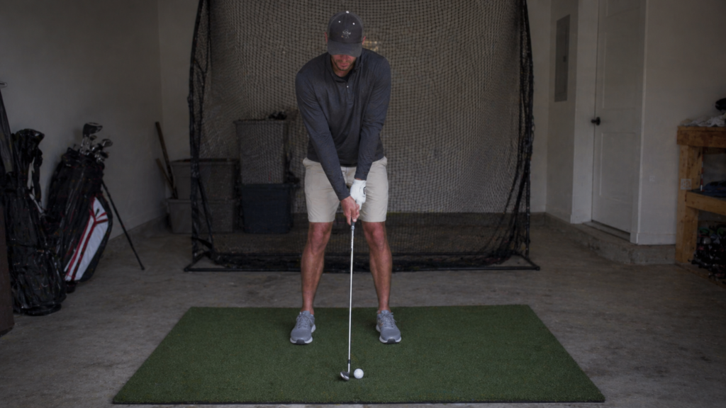 Golfer practicing a wedge pre-shot routine at home before making a calm training swing.