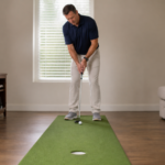 Golfer practicing a pre-putt routine at home on an indoor putting mat.