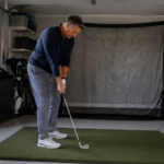 Golfer rehearsing a wedge movement at home to train swing thoughts before taking them to the course.